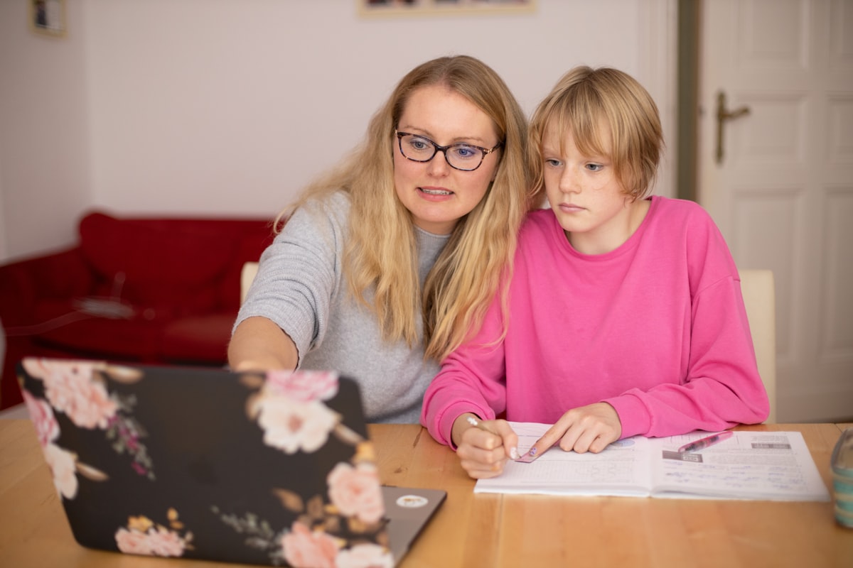 A parent helping their child with homework on a laptop